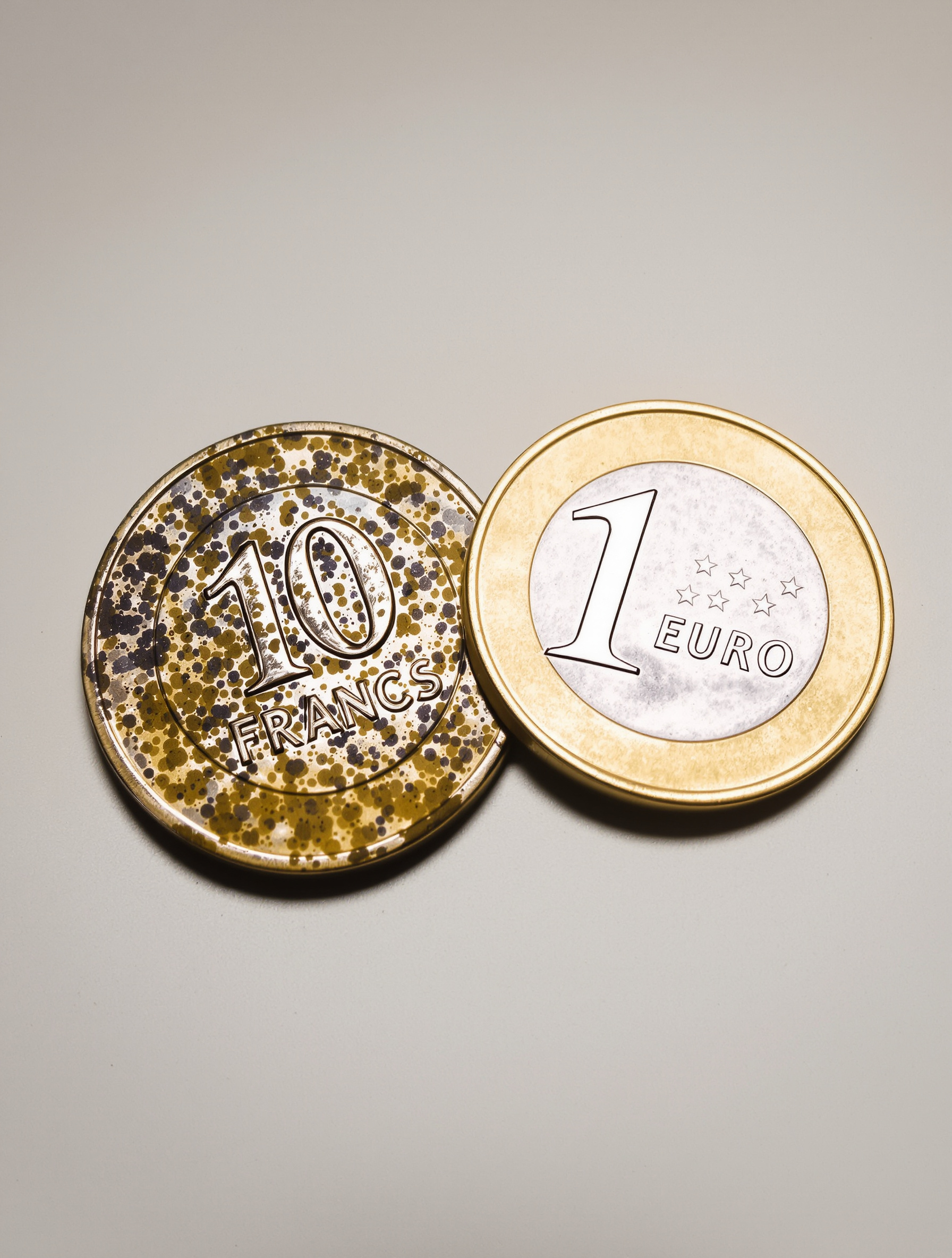 Vieille pièce de 10 francs usée à côté d'une pièce d'un euro brillante, illustrant l'érosion monétaire.