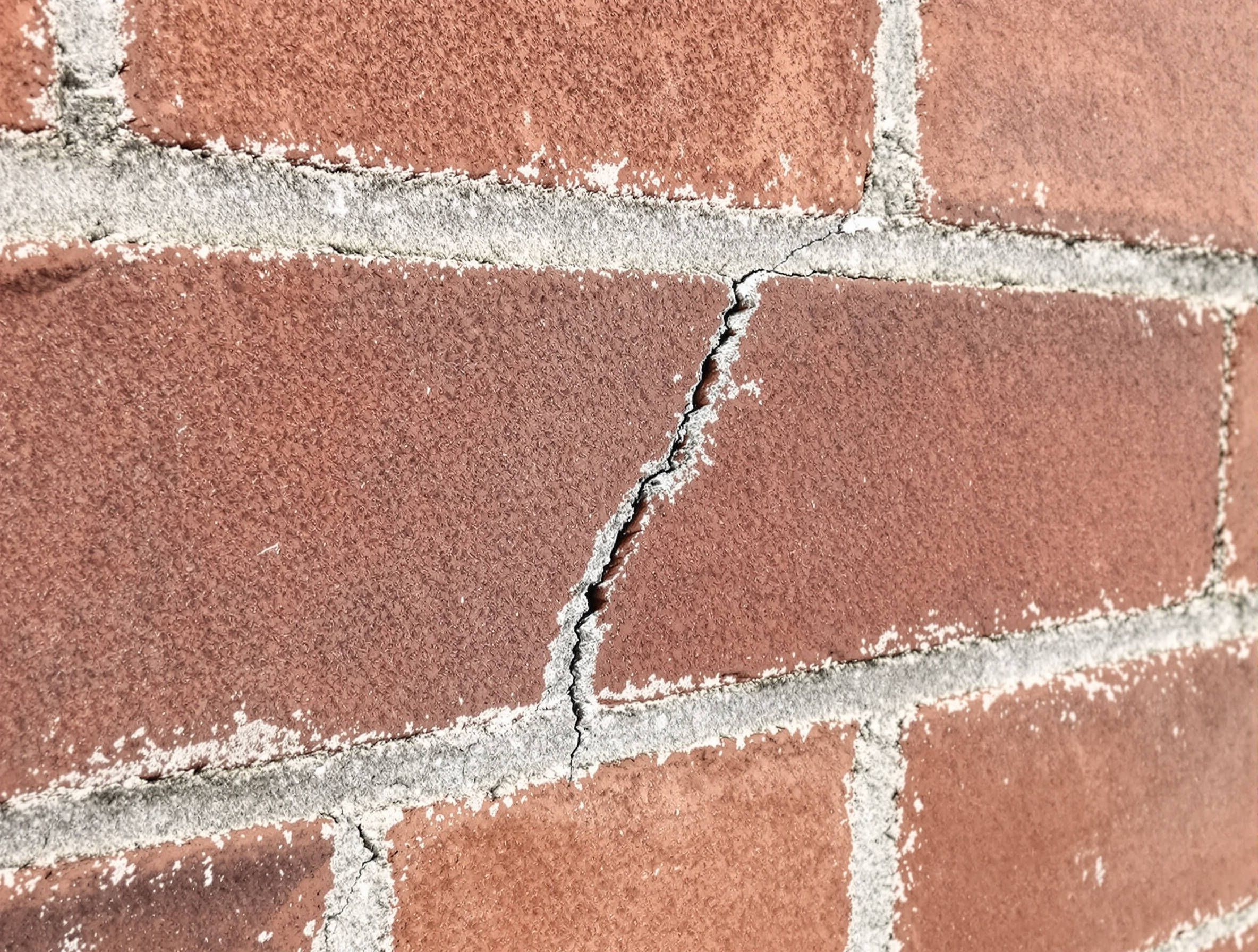 Fissure structurelle en escalier sur mur extérieur brique maison