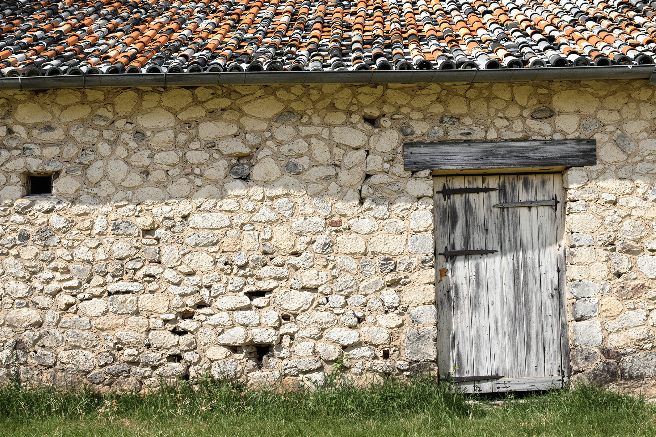 Façade d'une maison de campagne de caractère dans l'Allier avec fissures et toiture fatiguée