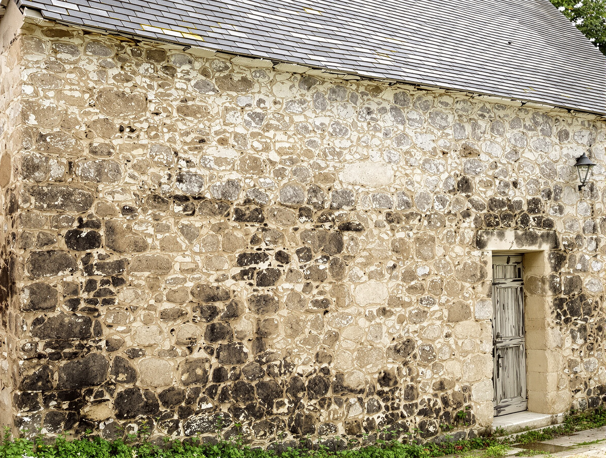 Maison ancienne en pierre typique de l'Aveyron avec traces d'humidité sur les murs.